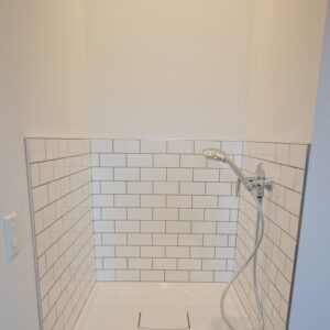 custom made dog shower with glossy white subway tile and chrome shower hardware