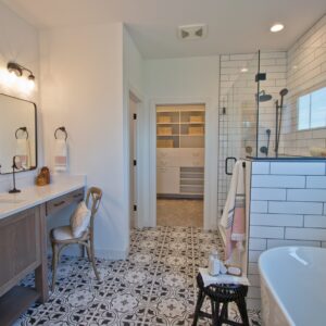 Looking into a black and white themed bathroom with vintage patterned tile installed on bathroom floor.