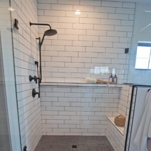 Contrasting black and white themed Bathroom with vintage tile patterns installed on floor, in front of a glass enclosed shower