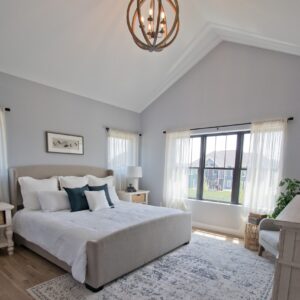 Master bedroom with hardwood floor and vaulted ceilings. A circular wood framed chandelier hangs from the ceiling