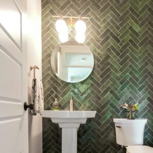 Powder room with green tile installed in herringbone pattern on wall from floor to ceiling