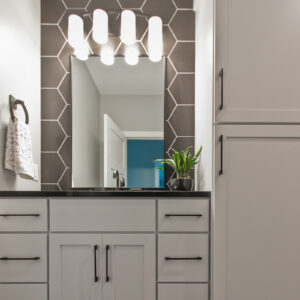black matte hexagon tile with white painted wood cabinets and black quartz countertop