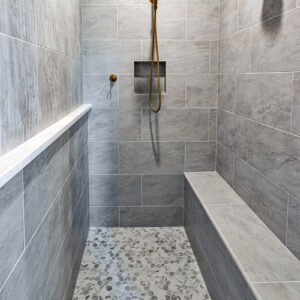 Classic Elegance Design, Custom shower with Schluter system, 12x24 fluted tile walls, Daltile porcelain tile in Brilliant White, sliced pebble floor, and built-in bench.