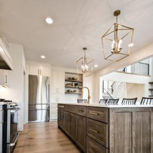 Classic Elegance Design, Medium natural stained kitchen island topped with a sleek white quartz countertop, installed over engineered hardwood flooring in Whitlock Beige from MSI’s McCarran collection