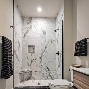 Stylish and modern, this 1st floor hall bathroom features striking black hexagon tile on the floor and Emser Contessa Oro matte tile on the shower walls, creating a sleek, contemporary look.