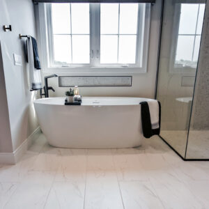 The primary bathroom is enhanced with Emser Contessa 12x24 Oro matte porcelain tile, offering a sleek and modern foundation with its timeless neutral tones.